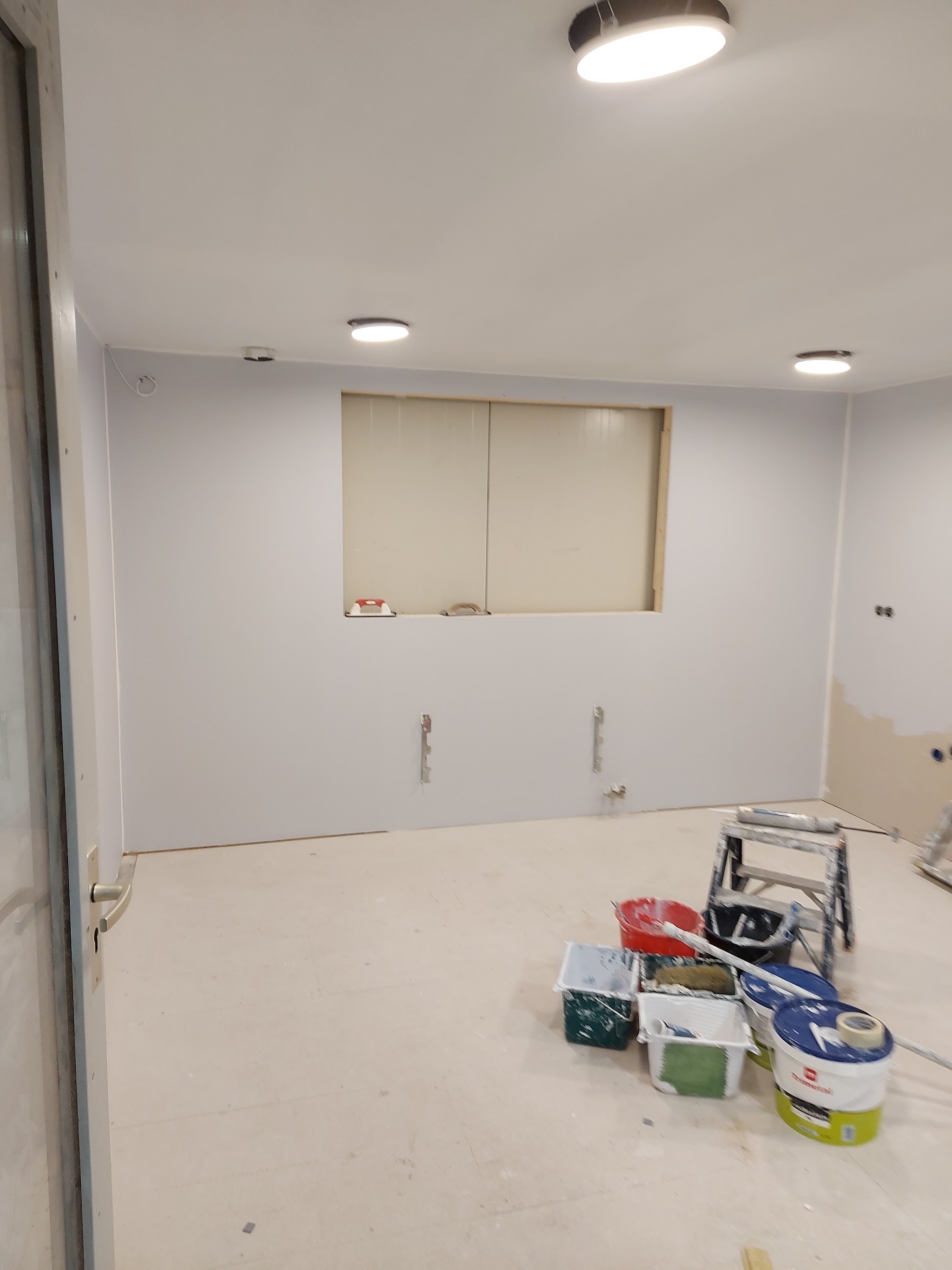 Lichte kamer met vers gesausde wanden en plafond, verfemmers op de vloer